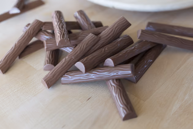 Lange Schokolade-Pralinen dienen als dekorativer Tortenrand.