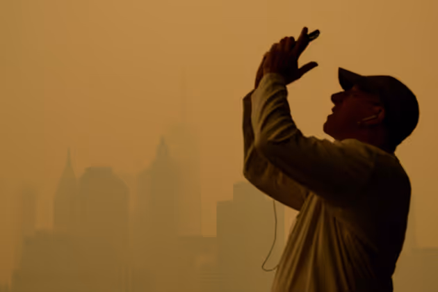 People take photos as smoke from the wildfires in Canada cause hazy conditions in New York City on June 7, 2023. Smoke from Canadaís wildfires has engulfed the Northeast and Mid-Atlantic regions of the US, raising concerns over the harms of persistent poor air quality. (Photo by ANGELA WEISS / AFP)
