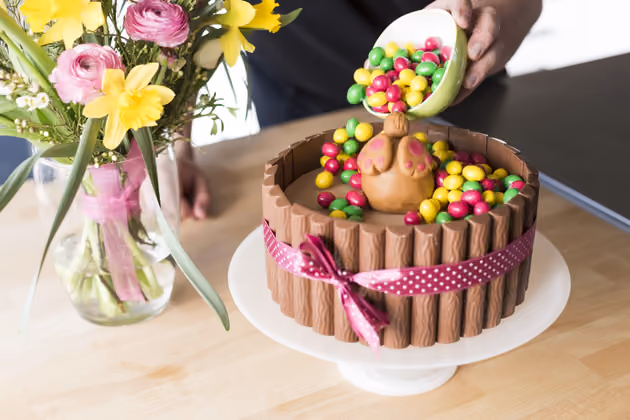 Die Schokolinsen vorsichtig auf die Torte schütten.