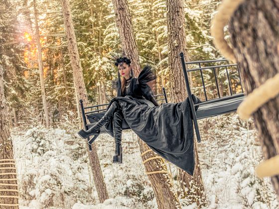 Model Chrissi präsentiert Schuhe von Buffalo auf einem Bett, das mitten im Wald an Bäumen baumelt.