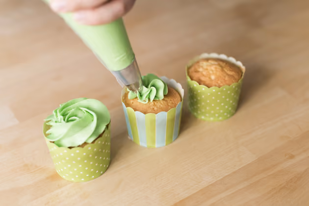Die Creme besteht aus gleichen Teilen Butter und Staubzucker sowie einigen Esslöffeln Vanillepudding. Beim Aufschlagen die Creme mit grüner Pastenfarbe einfärben. Dann in den Spritzsack füllen und auf den Cupcakes langsam aufspritzen.