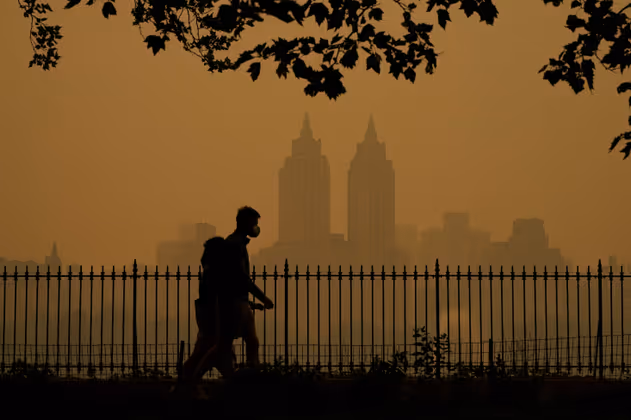 TOPSHOT - People walk in Central Park as smoke from wildfires in Canada cause hazy conditions in New York City on June 7, 2023. Smoke from Canadaís wildfires has engulfed the Northeast and Mid-Atlantic regions of the US, raising concerns over the harms of persistent poor air quality. (Photo by TIMOTHY A. CLARY / AFP)