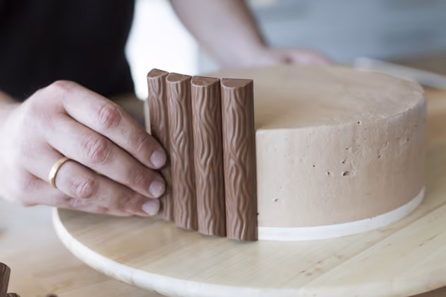Die Pralinen "klebt" Moschen nacheinander auf den Rand der Torte. Ein Kleber ist dafür nicht nötig, denn die Pralinen werden durch die Buttercreme festgehalten. Statt dieser kann auch Marmelade verwendet werden.