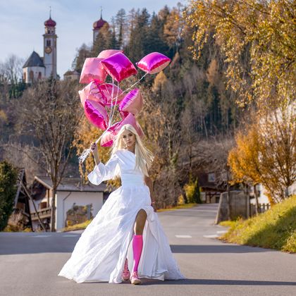 Model Michi trägt ein Brautkleid von Mei Kleid, die Kirche von Ampass thront eindrucksvoll im Hintergrund.