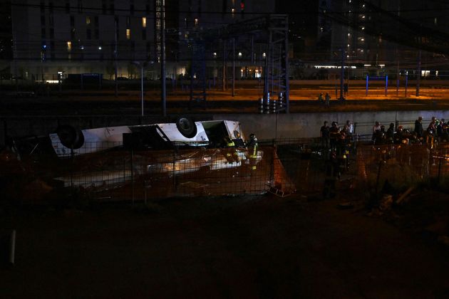 Firefighters work on the site of a bus accident on October 03, 2023 in Mestre, near Venice. At least 20 people were killed Tuesday when a bus plunged off a bridge in the northern Italian city of Venice, a city hall spokesman told AFP. The crash caused "at least 20 deaths, including two children," the spokesman said. Firefighters said the bus caught fire after careering off a bridge linking the Mestre and Marghera districts. (Photo by Marco SABADIN / AFP)