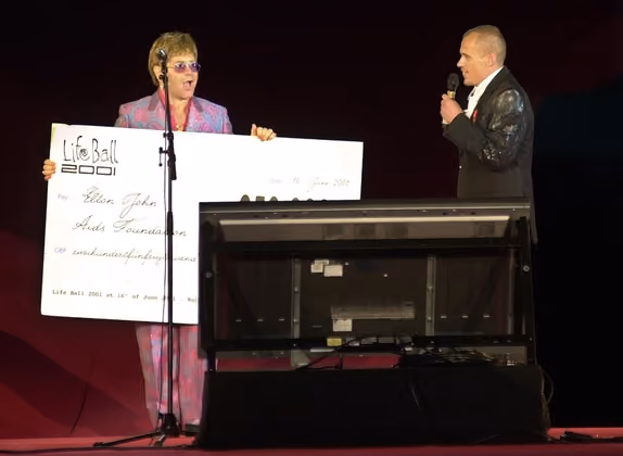 Life Ball 2001: Stargast Elton John (l.) mit einem Scheck über 520.000 Pfund für Ball-Organisator Gery Keszler (r.).