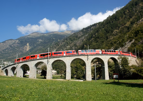 Der Bernina Express auf dem bekannten Kreisviadukt bei Brusio. Eine Fahrt von den Gletschern zu den Palmen.