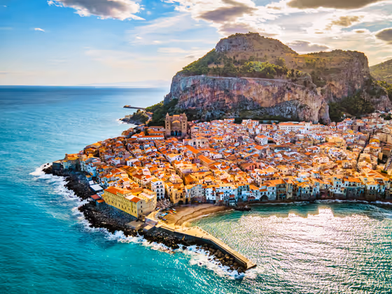 Drone view from above at the old town of Cefalu at sunset, medieval village of Sicily island, Province of Palermo, Italy. Europe. Cathedral of Cefalu