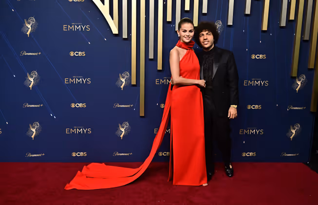 Benny Blanco elegant in Schwarz und mit der Royal Oak Frosted Gold von Audemars Piguet, Selena Gomez in roter Louis-Vuitton-Robe und Diamantschmuck von Tiffany & Co.