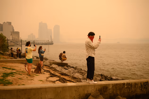 People take photos of the Manhattan skyline during heavy smog in New York on June 6, 2023. Smoke from Canadaís wildfires has engulfed the Northeast and Mid-Atlantic regions of the US, raising concerns over the harms of persistent poor air quality. (Photo by Ed JONES / AFP)