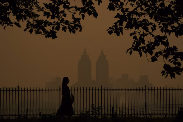 People wlak in Central Park as smoke from wildfires in Canada cause hazy conditions in New York City on June 7, 2023. Smoke from Canadaís wildfires has engulfed the Northeast and Mid-Atlantic regions of the US, raising concerns over the harms of persistent poor air quality. (Photo by TIMOTHY A. CLARY / AFP)