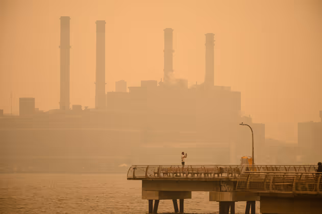 A man takes photos from a pier before the Manhattan skyline shrouded in heavy smog in New York on June 7, 2023. Smoke from Canadaís wildfires has engulfed the Northeast and Mid-Atlantic regions of the US, raising concerns over the harms of persistent poor air quality. (Photo by Ed JONES / AFP)